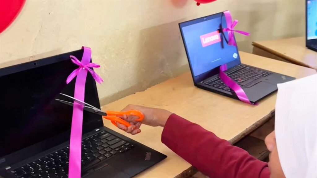 Student cutting the ribbon on a new laptop in the Kisannagar AI lab