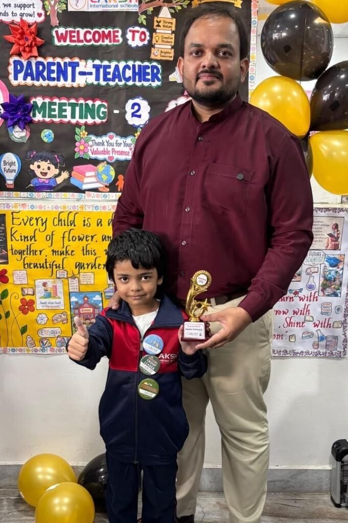 A young topper receives a Topper trophy at Parent Teacher Meeting 2, LAKSH Vijaynagar Colony