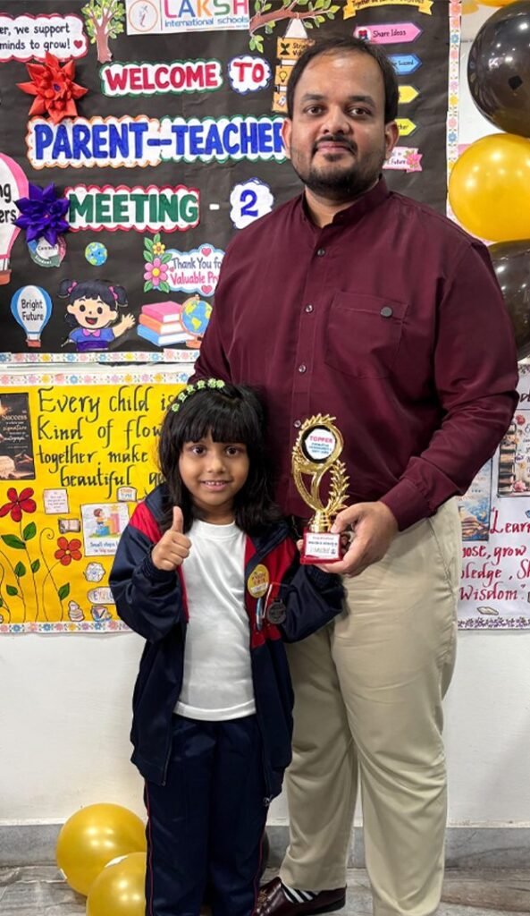 A smiling topper holds her Topper trophy at the LAKSH Vijaynagar Colony parent teacher meeting